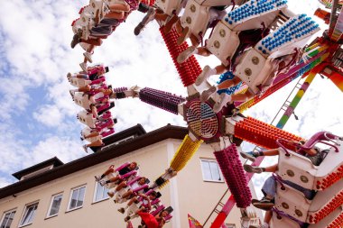 Villach, Avusturya - 30 Temmuz 2025: Açık mavi gökyüzüne karşı heyecanlı biniciler ve canlı renklerin yer aldığı Villacher Kirchtag festivalinde eğlenceli bir gezinti