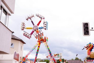 Villach, Avusturya - 30 Temmuz 2025: Villacher Kirchtag festivalinde neşeli dekorasyonlar ve neşeli atmosferle çevrili renkli dönme dolap