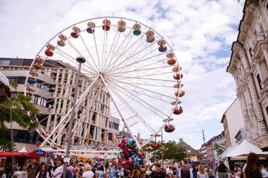 Villach, Avusturya - 30 Temmuz 2025: Vibrant dönme dolap Villacher Kirchtag festivalinde, kalabalıklar arka planda renkli tezgahların ve şenliklerin keyfini çıkarıyor