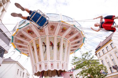 Avusturya 'nın Villach kenti - 30 Temmuz 2025: Avusturya' daki Villacher Kirchtag festivalinde neşeli biniciler ve güzel çevre mimarinin yer aldığı canlı salıncaklı atlıkarınca