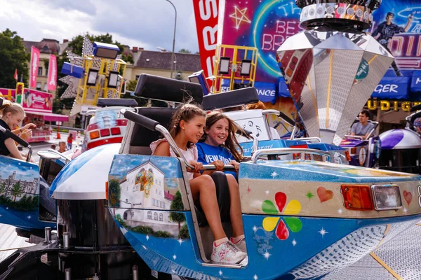 Villach, Avusturya - 30 Temmuz 2025: İki kız arkada canlı festival dekorasyonlarıyla Villacher Kirchtag 'de gülüyor ve eğleniyorlar