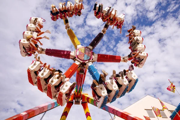 Villach, Avusturya - 30 Temmuz 2025: Villacher Kirchtag Festivali 'nde eğlenceli bir yolculuk, yukarıda dönen heyecanlı binicilerin parlak bir gökyüzü ile çevrili