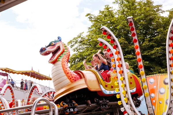 Villach, Avusturya - 30 Temmuz 2025 Villacher Kirchtag lunaparkındaki renkli ejderha hız treni şenlikli bir atmosferde neşe ve heyecanla süvarileri heyecanlandırıyor.