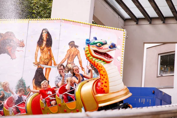 Villach, Avusturya - 30 Temmuz 2025: Villacher Kirchtag festivalinde ejderha temalı lunapark treni, heyecan verici gezinti ve şenlikli ortam ortamının keyfini çıkaran mutlu çocuklarla dolu