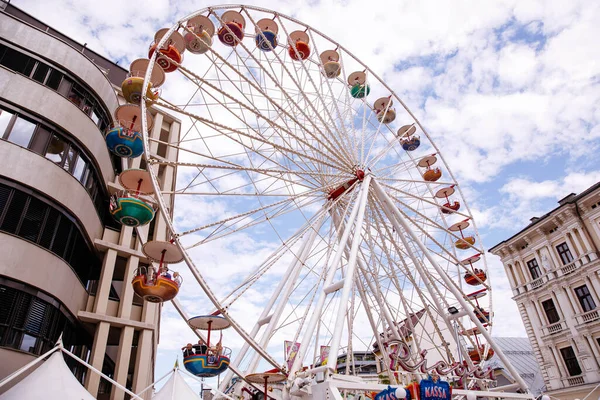 Villach, Avusturya - 30 Temmuz 2025: Villacher Kirchtag festivalinde tarihi mimari ve canlı ambiyansla çevrili renkli dönme dolap