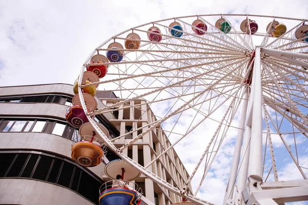 Villach, Avusturya - 30 Temmuz 2025: Renkli dönme dolap Villacher Kirchtag 'deki çağdaş binanın yanında duruyor, canlı ve şenlikli bir ortam yaratıyor.