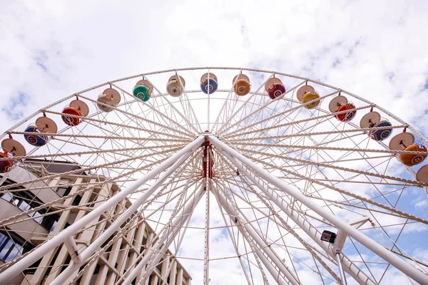 Villach, Avusturya - 30 Temmuz 2025: Dönme dolap parlak bir gökyüzünün altında, canlı kulübeler ve modern binaların bulunduğu, Villacher Kirchtag 'in ruhunu somutlaştıran,