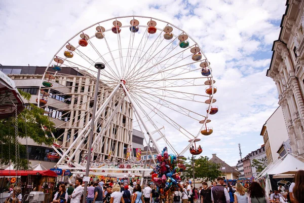 Villach, Avusturya - 30 Temmuz 2025: Villacher Kirchtag festivalinde renkli dönme dolap, hareketli atmosferin ve neşeli tezgahların keyfini çıkaran kalabalık