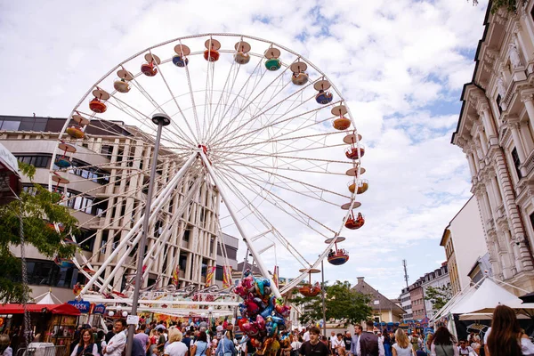 Villach, Avusturya - 30 Temmuz 2025: Vibrant dönme dolap Villacher Kirchtag festivalinde, kalabalıklar arka planda renkli tezgahların ve şenliklerin keyfini çıkarıyor