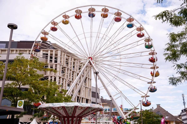 Villach, Avusturya - 30 Temmuz 2025: Villacher Kirchtag festivalinde neşeli atmosfer ve şenliğin tadını çıkaran neşeli ziyaretçilerle çevrili renkli dönme dolap