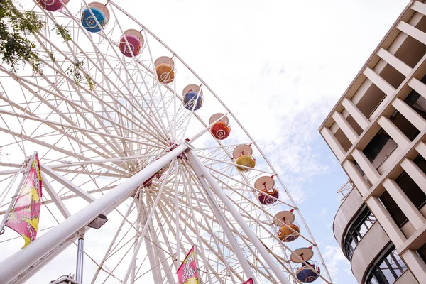 Villach, Avusturya - 30 Temmuz 2025: Renkli dönme dolap Villacher Kirchtag 'deki çağdaş binanın yanında duruyor, neşeli ve neşeli bir ortam yaratıyor.