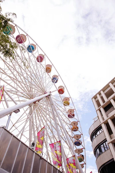 Villach, Avusturya - 30 Temmuz 2025: Avusturya 'daki Villacher Kirchtag festivalinde renkli pankartlar ve çağdaş binalarla çevrili dönme dolap