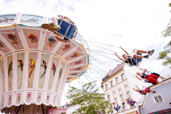 Villach, Avusturya - 30 Temmuz 2025: Çocuklar canlı dekorasyon ve neşeli ambiyansla çevrili Villacher Kirchtag festivalinde salıncakta sallanırken eğleniyorlar