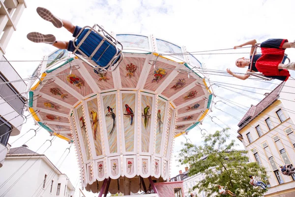 Avusturya 'nın Villach kenti - 30 Temmuz 2025: Avusturya' daki Villacher Kirchtag festivalinde neşeli biniciler ve güzel çevre mimarinin yer aldığı canlı salıncaklı atlıkarınca