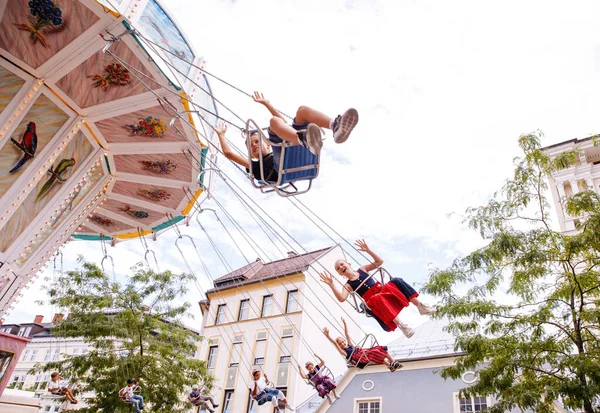 Villach, Avusturya - 30 Temmuz 2025: Çocuklar arka planda renkli dekorasyonlar ve büyüleyici binalarla Villacher Kirchtag 'da salıncaklı atlıkarıncada eğleniyorlar
