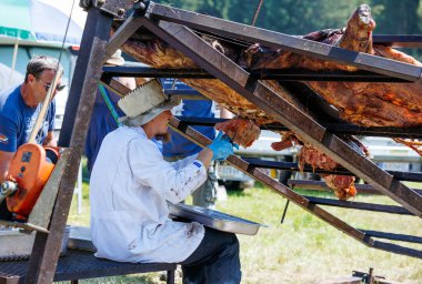 Ossiacher Tauern, Avusturya - 10 Ağustos 2025: Beyaz önlüklü erkek şef Rindfleischfest 'te festival katılımcıları ve açık hava etkinlikleriyle çevrili kızarmış et oyuyor