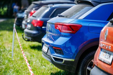 Ossiacher Tauern, Avusturya - 10 Ağustos 2025: Mavi SUV Rindfleischfest 'te birden fazla aracın yanına park edilmiş, yemyeşil çimenler ve hareketli bir ortam ile çevrili.