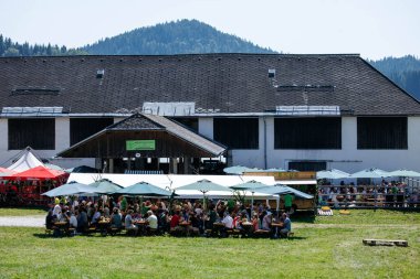 Ossiacher Tauern, Avusturya - 10 Ağustos 2025: Rindfleischfest, dağlarla ve yeşilliklerle çevrili çadırların altında neşeli bir kalabalığa ev sahipliği yapıyor.