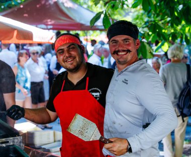 Ossiacher Tauern, Avusturya - 10 Ağustos 2025: İki erkek aşçı Rindfleischfest 'te ızgara yapıyor, kalabalığa karışıyor ve festival ortamında aşçılık becerileri sergiliyor