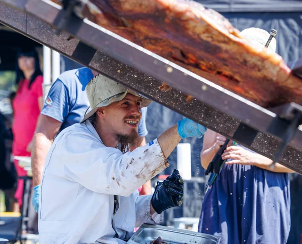 Ossiacher Tauern, Avusturya - 10 Ağustos 2025: Erkek aşçı festival katılımcıları ve hareketli ambiyansla çevrili Rindfleisfest yemek hazırlıyor
