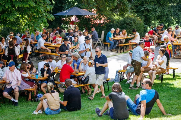 Ossiacher Tauern, Avusturya - 10 Ağustos 2025: Rindfleischfest, yeşil alanlarla çevrili ortak masalarda yemek ve içeceklerin keyfini çıkaran insanlarla dolu canlı bir açık hava toplantısına ev sahipliği yapıyor.