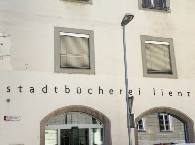 Lienz, Avusturya - 18 Eylül 2025: Stadtbucherei Lienz, ziyaretçileri kütüphanenin kaynakları ve kamu alanlarını keşfetmeye davet eden geniş pencereli çağdaş bir cepheye sahip