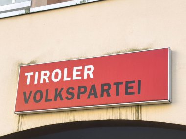 Lienz, Avusturya - 18 Eylül 2025: Tiroler Volkspartei tabelası, parlak kırmızı rengini ve kalın harflerini vurgulayarak, dış yüzeyin inşasında belirgin bir rol oynadı
