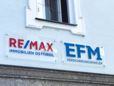 Lienz, Avusturya - 18 Eylül 2025: RE / MAX Immobilien Osttirol ve EFM Versicherungsmakler tabelaları, ticari markaların ve hizmetlerin altını çizerek dış yapı üzerinde sergilendi