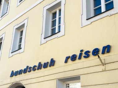 Lienz, Avusturya - 18 Eylül 2025: Bundschuh Reisen seyahat acentesi pencereli parlak sarı bir duvarda sergilenerek ziyaretçiler için davetkar bir ortam yarattı