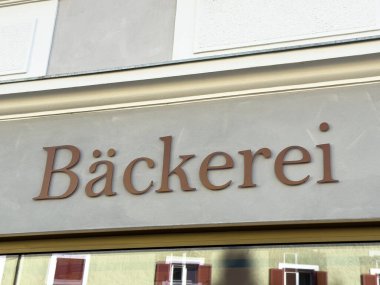 Lienz, Avusturya - 18 Eylül 2025: Fırının dış yüzeyinde belirgin bir şekilde gösterilen Backerei tabelası, taze pişmiş malların cazibesini ve işçiliğini vurguluyor