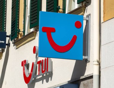 Lienz, Avusturya - 18 Eylül 2025: TUI logosu canlı kentsel bir çevrede marka kimliğini vurgulayan kırmızı gülen yüz tasarımlı mavi bir arka plana sahiptir