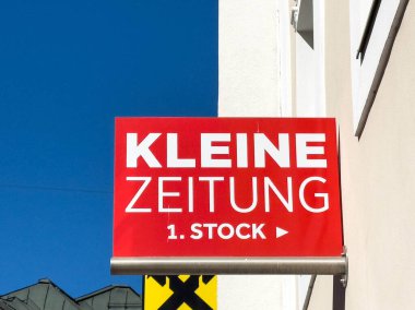 Lienz, Avusturya - 18 Eylül 2025: Kırmızı işaret Kleine Zeitung 'u inşaat alanında, parlak renkler ve şehir ortamında berrak markalaşmayı vurguluyor