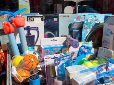 Lienz, Avusturya - 18 Eylül 2025: Mağaza vitrininde canlı çocuk oyuncakları koleksiyonu, su tabancaları ve renkli ambalajlar sergileniyor