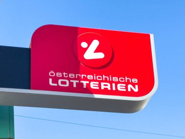Lienz, Avusturya - 18 Eylül 2025: Osterreichische Lotterien açık mavi gökyüzüne karşı belirgin bir şekilde gösterilerek, markanın canlı kırmızı logosu ve tasarımı vurgulandı