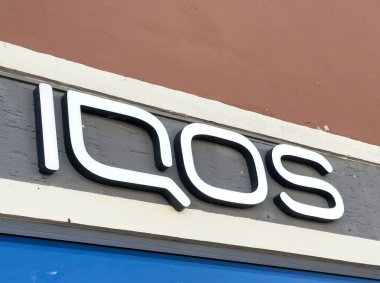 Lienz, Avusturya - 18 Eylül 2025: IQOS logosu, canlı kentsel bir ortamda çağdaş markalaşma ve tasarım unsurlarını vurgulayan bir mağaza vitrininde yer almaktadır.