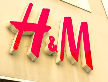 Lienz, Avusturya - 18 Eylül 2025: H & M logosu mağaza vitrininde sergilenmekte olup, renkli ve çağdaş tarzını perakende seti olarak vurgulamaktadır.