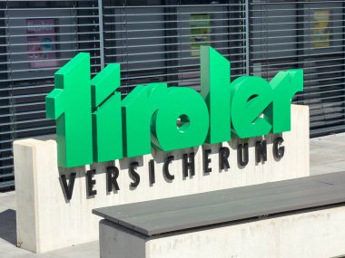 Lienz, Avusturya - 18 Eylül 2025: Tiroler Versicherung tabelası, çağdaş binanın dış tasarımını geliştiren koyu yeşil harflerle göze çarpıyor