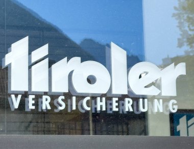 Lienz, Avusturya - 18 Eylül 2025: Tiroler Versicherung logosu cam pencerede belirgin bir şekilde yer alıyor, kentsel çevreleri yansıtıyor ve modern markalaşmayı vurguluyor