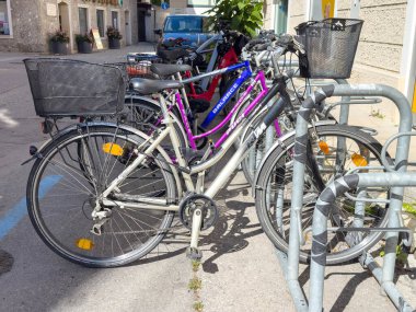 Lienz, Avusturya - 18 Eylül 2025: Bisikletler güneş ışığı altında bir bisiklet parkına park edilmiş, farklı renkler ve tasarımlar sergileniyor, kentsel bisiklet kültürünü vurguluyorlar