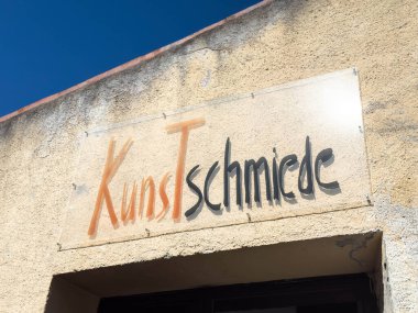 Lienz, Avusturya - 18 Eylül 2025: Kunstschmiede tabelaları parlak renklerle kaplanmış, güneşli bir ortamda yaratıcılığa ve sanatsal ifadeye davetiye çıkarıyor