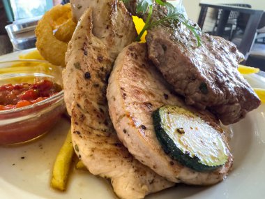 Izgara tavuk ve biftek tabağında kabak ve soğan halkaları..