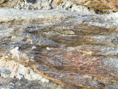 Katmanlı dokuya sahip yıpranmış kaya yüzeyinin yakın çekimi.