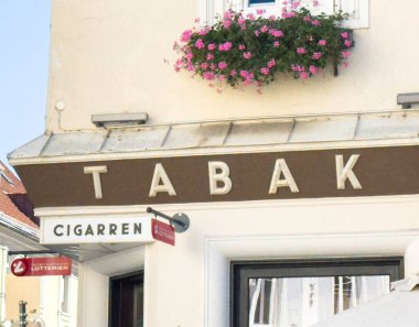 Wolfsberg, Avusturya - 19 Eylül 2025: TABAK mağazası renkli çiçekler ve açık bir tabela içeriyor ve Avrupa 'nın pitoresk bir bölgesinde hoş bir ortam yaratıyor