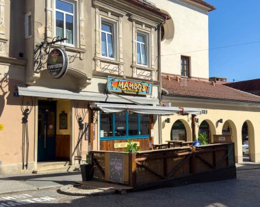 Wolfsberg, Avusturya - 19 Eylül 2025: Mambo 'nun restoranında, tarihi binaların bulunduğu pitoresk bir şehir alanına yerleştirilmiş renkli tabela ve açık hava oturma yerleri yer alıyor.