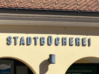 Wolfsberg, Avusturya - 19 Eylül 2025: Stadtbucherei tabelaları parlak sarı bir arkaplanda modern harflerin yer aldığı bir binada belirgin bir şekilde gösterildi