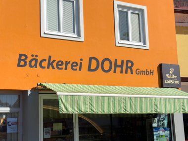 Wolfsberg, Avusturya - 19 Eylül 2025: Pastane Dohr turuncu renkli ve yeşil tenteli, müşterileri lezzetli fırınlanmış yiyeceklerin tadına varmaya davet ediyor.