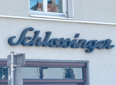 Wolfsberg, Avusturya - 19 Eylül 2025: Schlossinger tabelası modern kentsel arkaplana karşı stil harflerini vurgulayarak bina cephesinde sergilendi