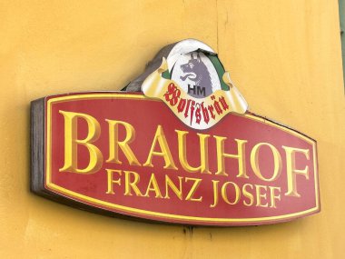 Wolfsberg, Avusturya - 19 Eylül 2025: Franz Josef 'in Brauhof tabelâsı, Bavyera bira kültürünü vurgulayan ve ambiyansı davet eden parlak sarı bir duvara dayanmıştır.