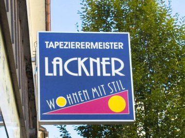 Wolfsberg, Avusturya - 19 Eylül 2025: Lackner için imza, bir duvar kağıdı servisi, yeşil bir arkaplan karşısında parlak renkler ve modern tasarım sergiliyor