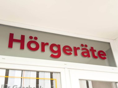 Wolfsberg, Avusturya - 19 Eylül 2025: Mağaza vitrinindeki korkunç tabela, şirketin topluma işitme cihazları ve işitsel hizmetler sağlamadaki kararlılığını vurguluyor